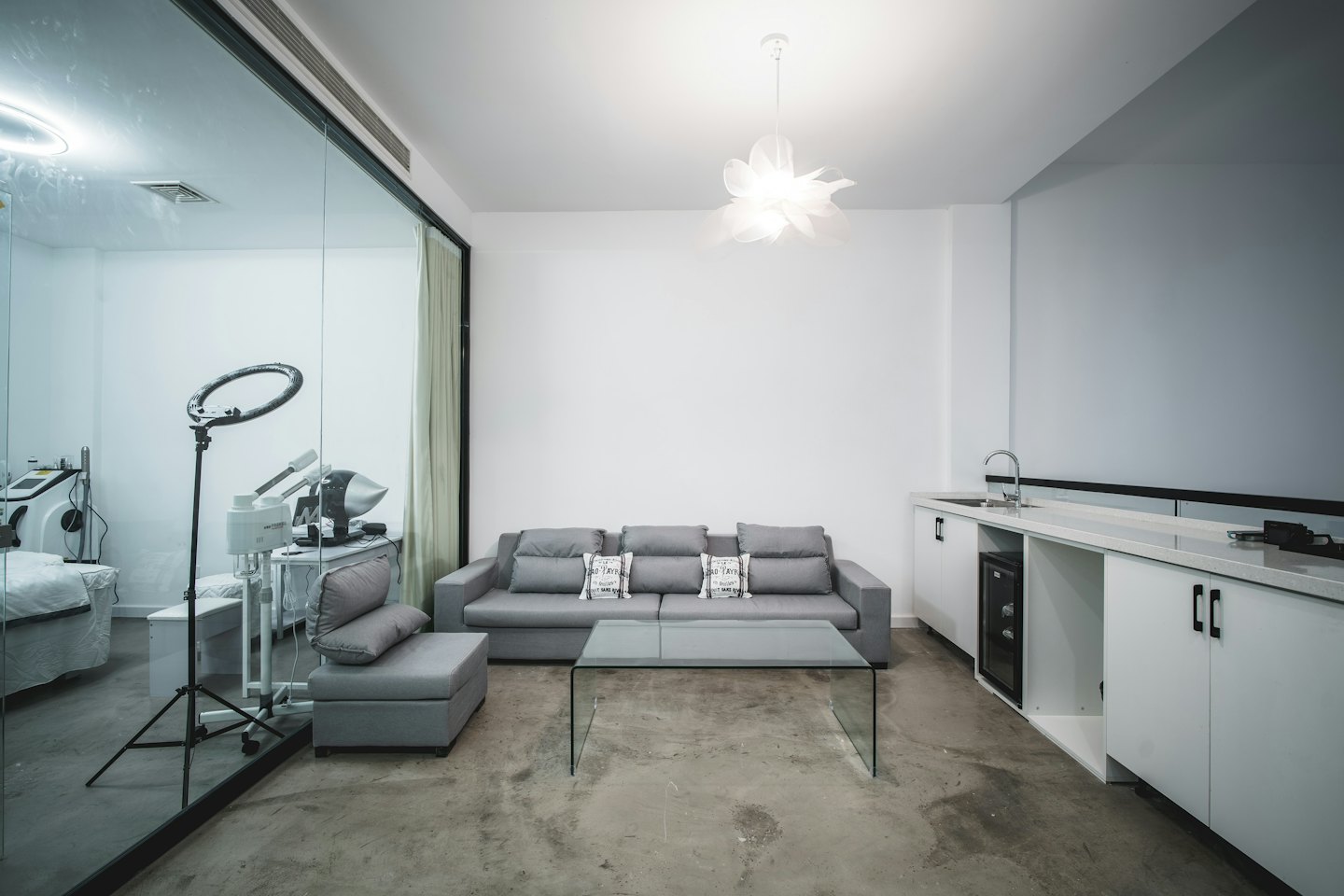 Modern waiting area with grey sofa and view of treatment room.